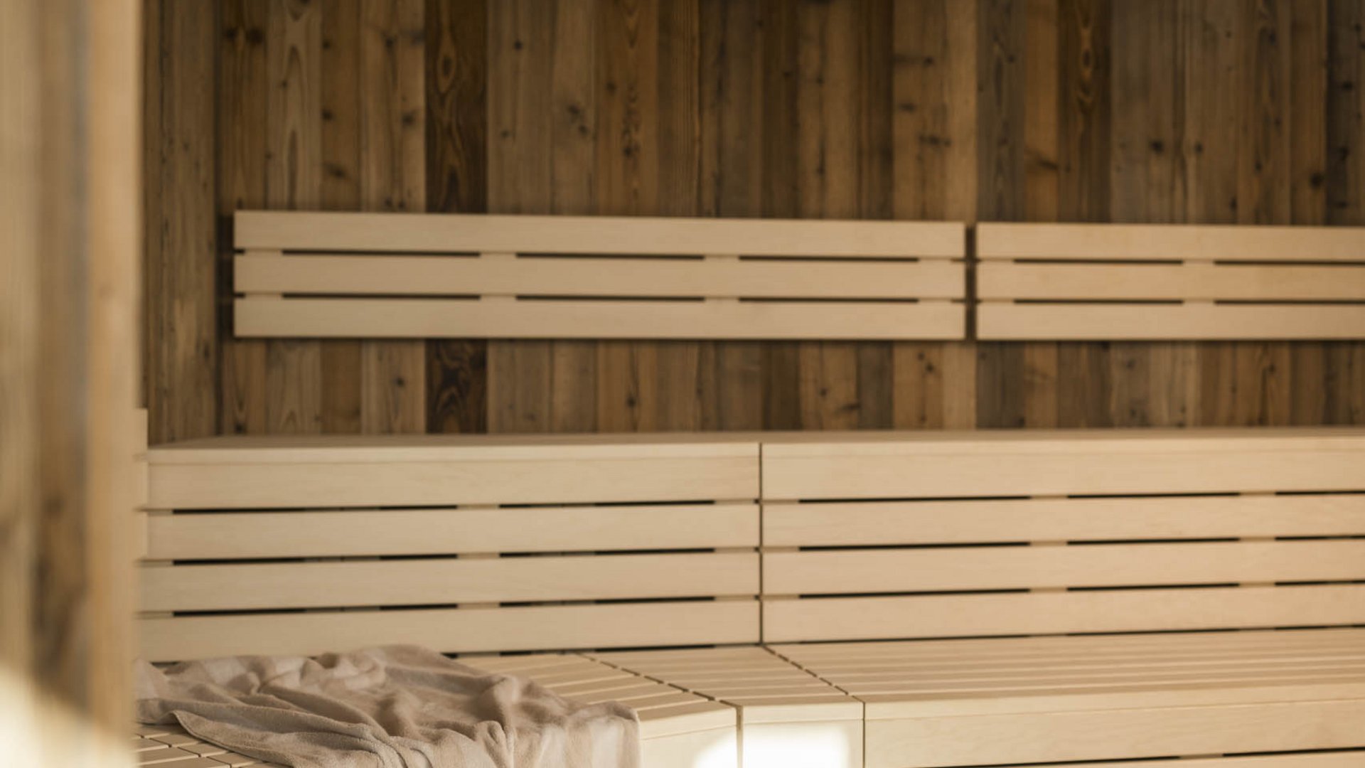 Interior of bright sauna with wooden walls and a towel on the bench