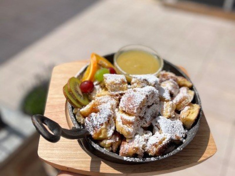 Die Cervosa Alm auf 2 000 Metern Kaiserschmarrn mit Puderzucker und Früchten auf Holzbrett serviert