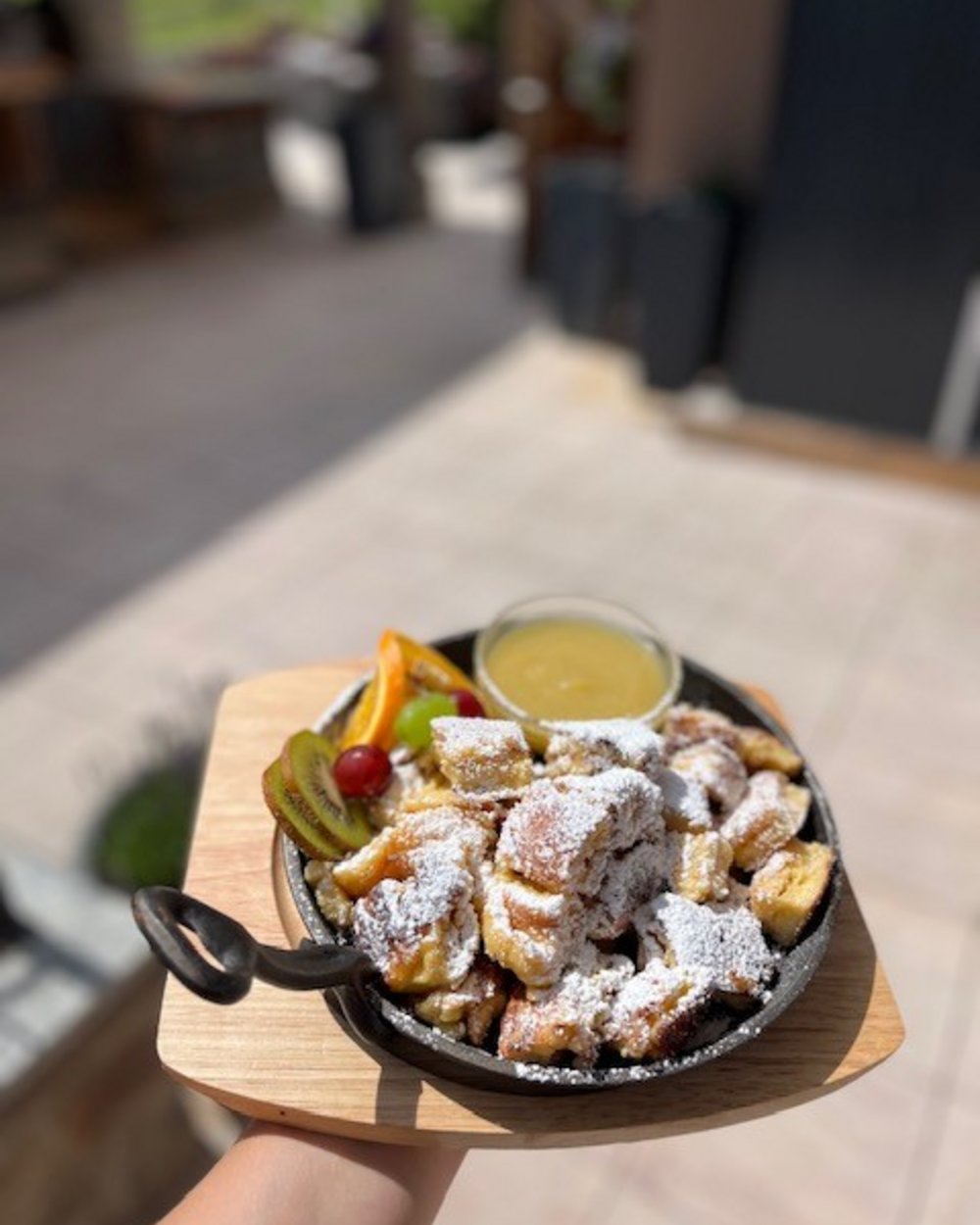 Kaiserschmarrn mit Puderzucker und Früchten auf Holzbrett serviert