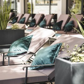 Liegen mit grünen Kissen in einem hellen, modernen Innenbereich mit Pflanzen