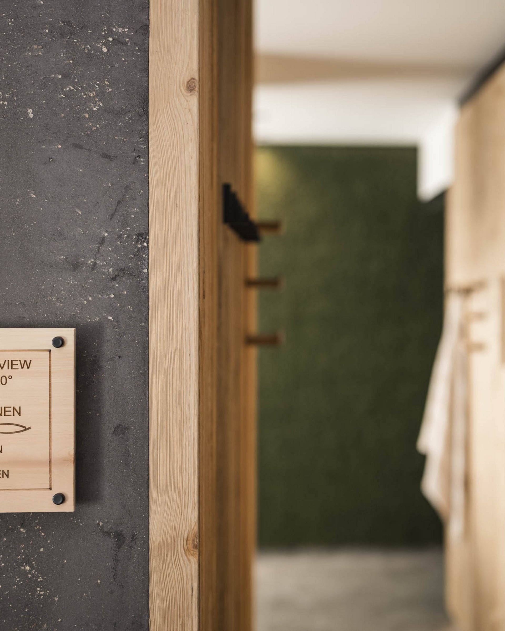 Wooden sign indicating sauna and ice fountain next to wooden lockers on dark wall