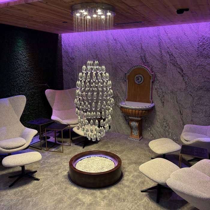 Moderner Lounge-Bereich mit Hängelampe, bequemen Sesseln und Steinwand