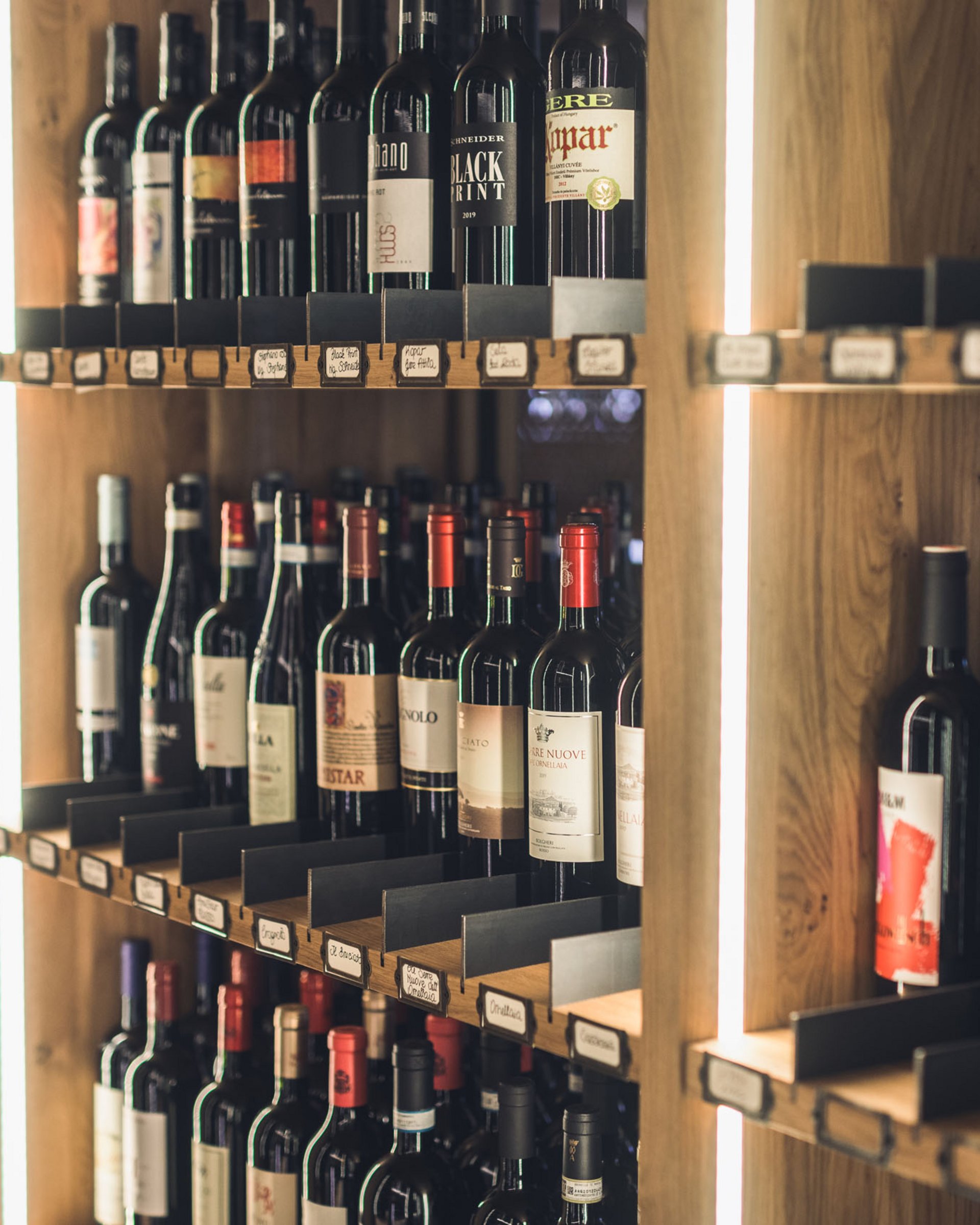 Shelves filled with various wine bottles in a wooden rack with lighting
