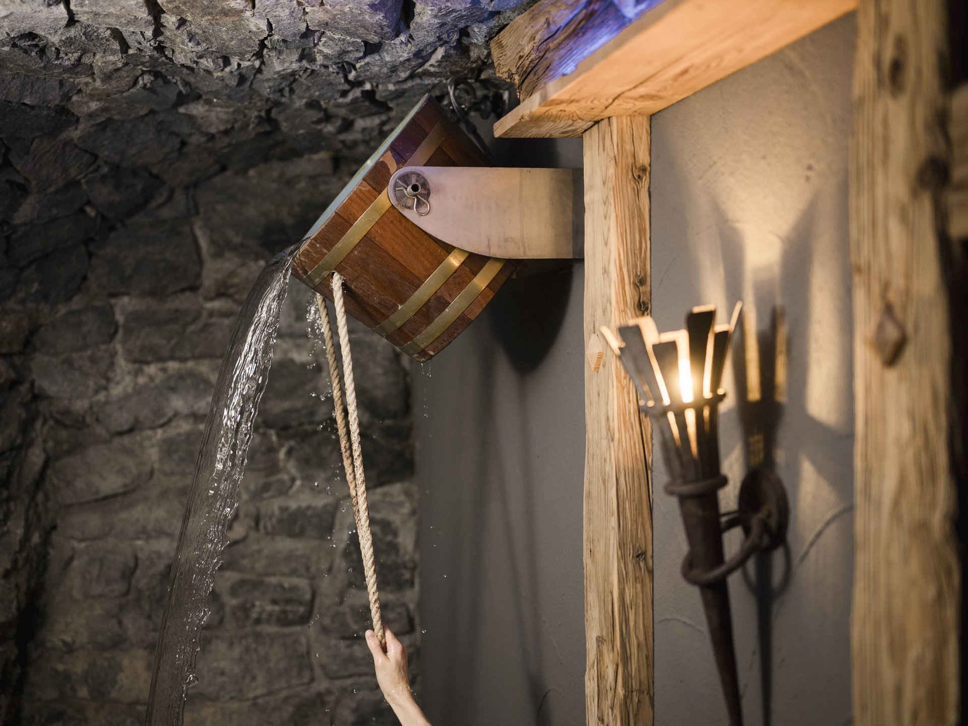 Water pouring from a wooden tipping bucket in a rustic stone room