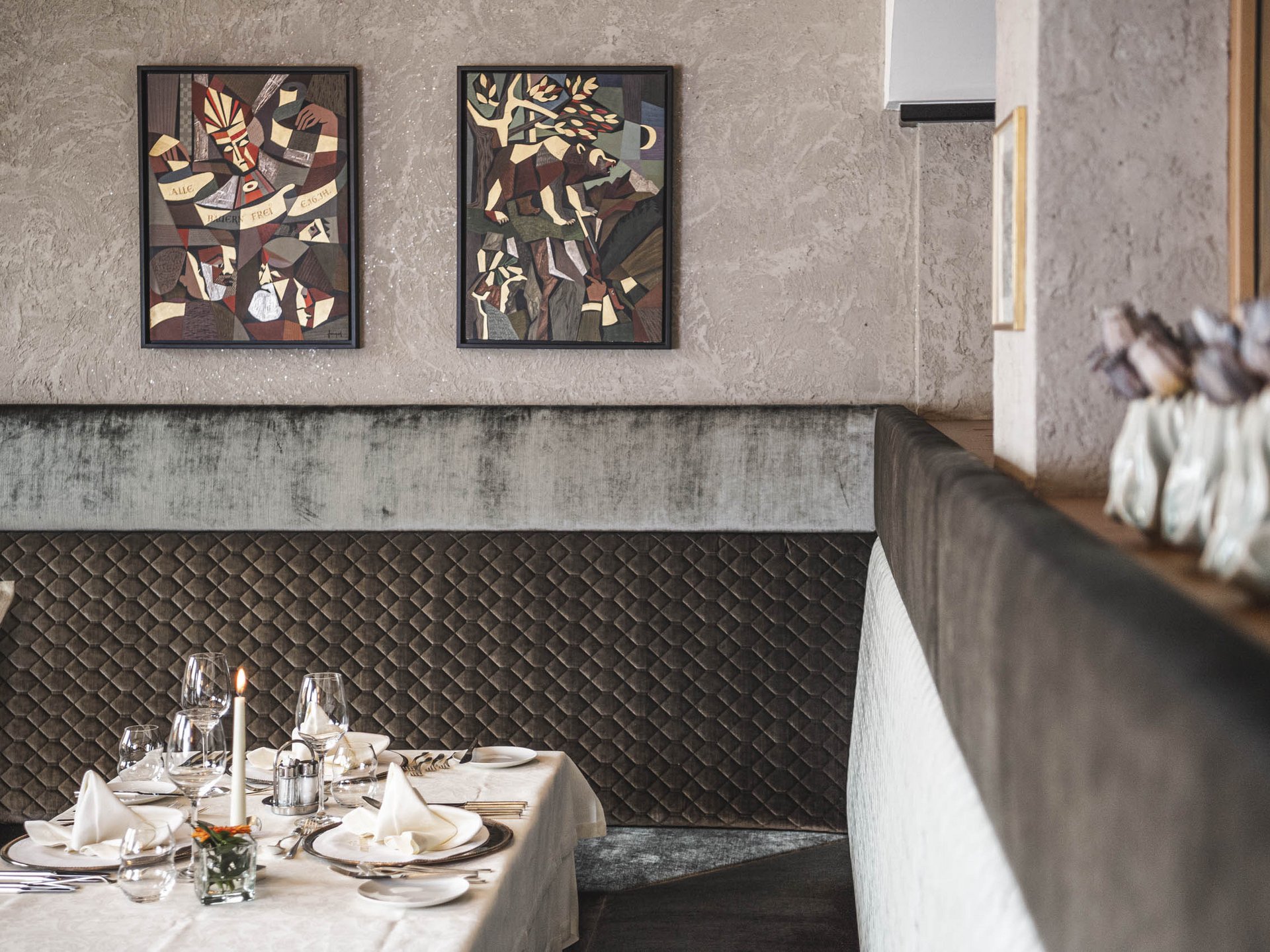 Feel-good holiday at our 5-star hotel in Serfaus Elegant table setting with candle, artwork, and upholstered wall in a restaurant