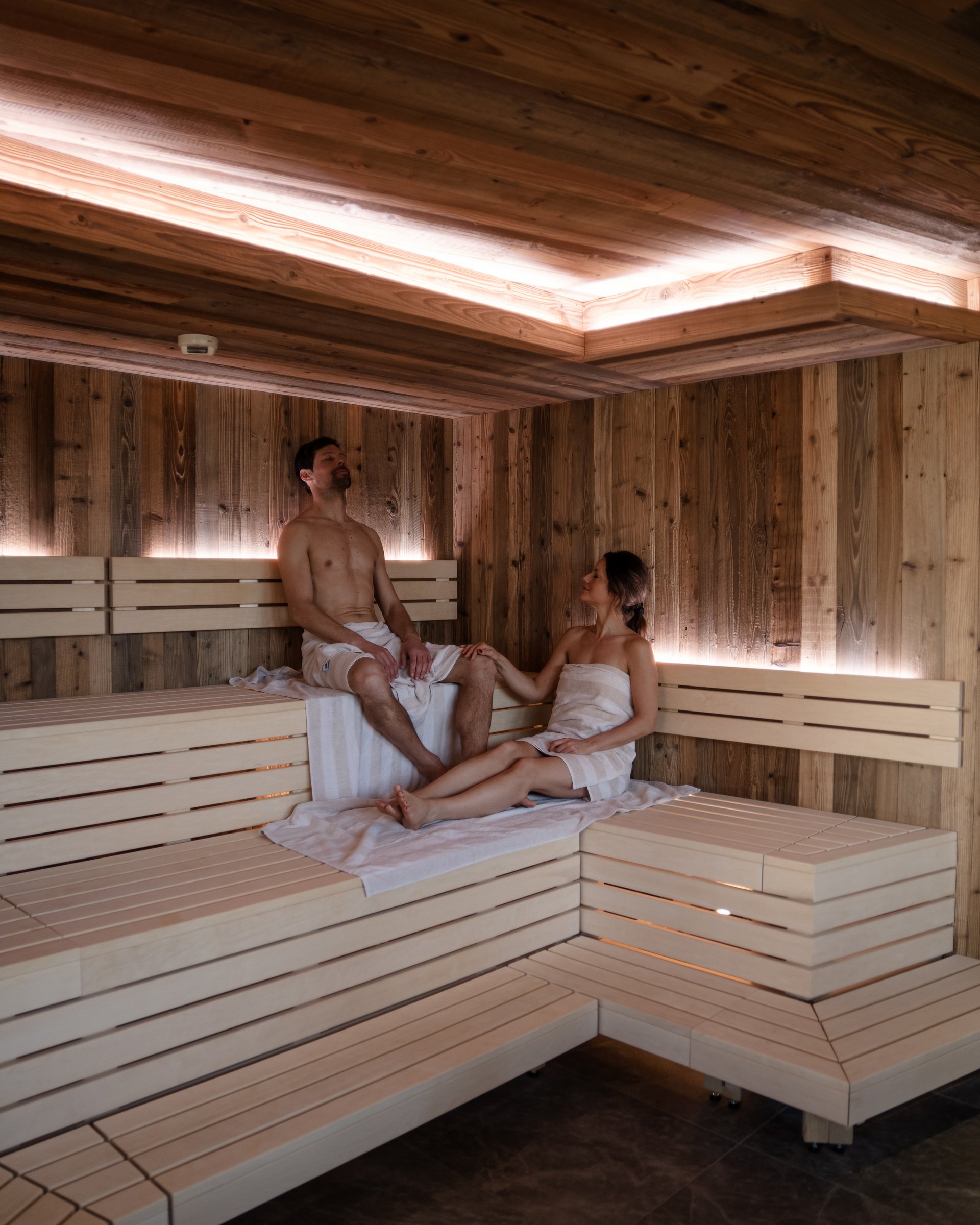 Paar entspannt in einer modernen Holzsauna mit indirekter Beleuchtung