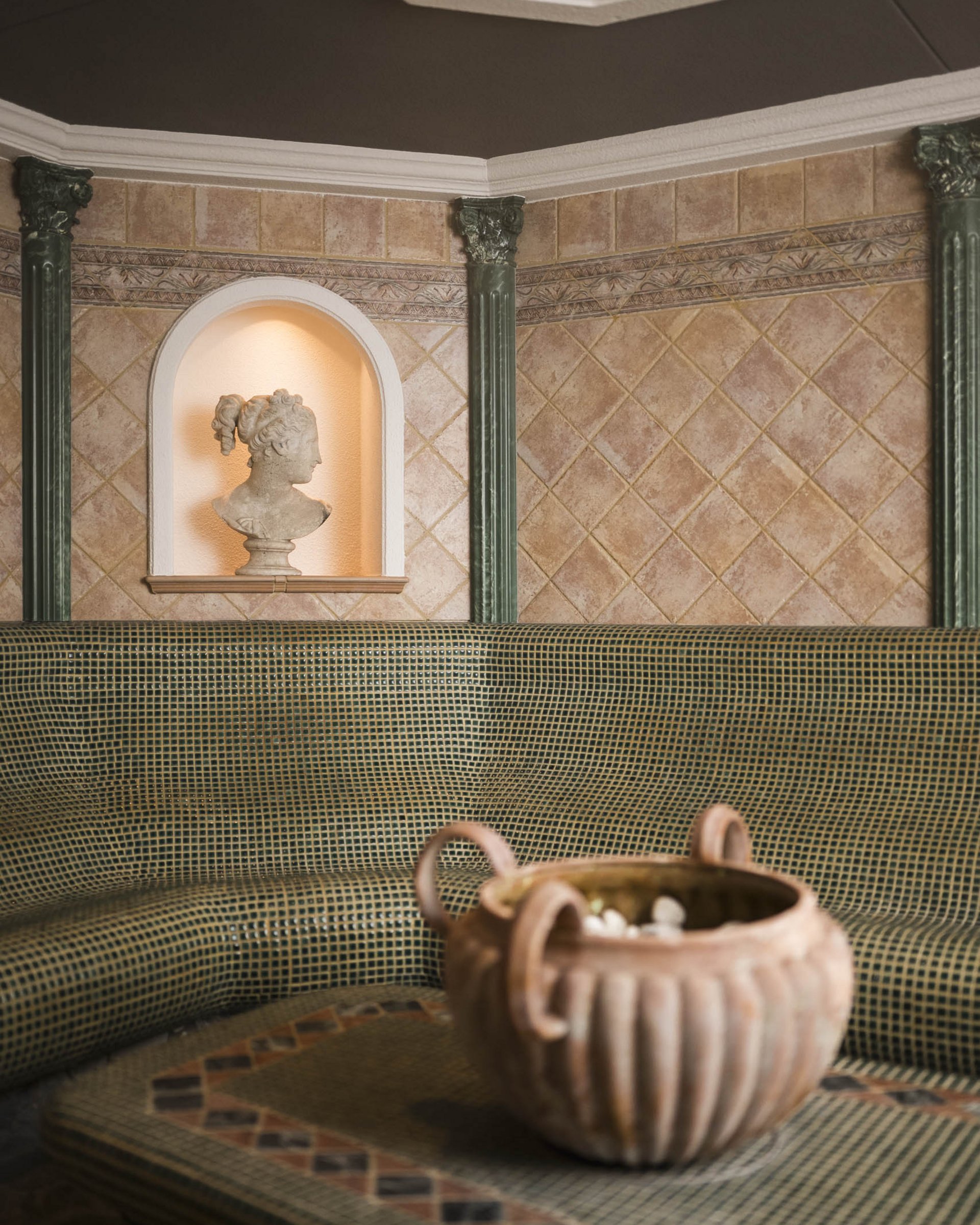 Circular mosaic seating area with antique bust and decorative ceramic pot