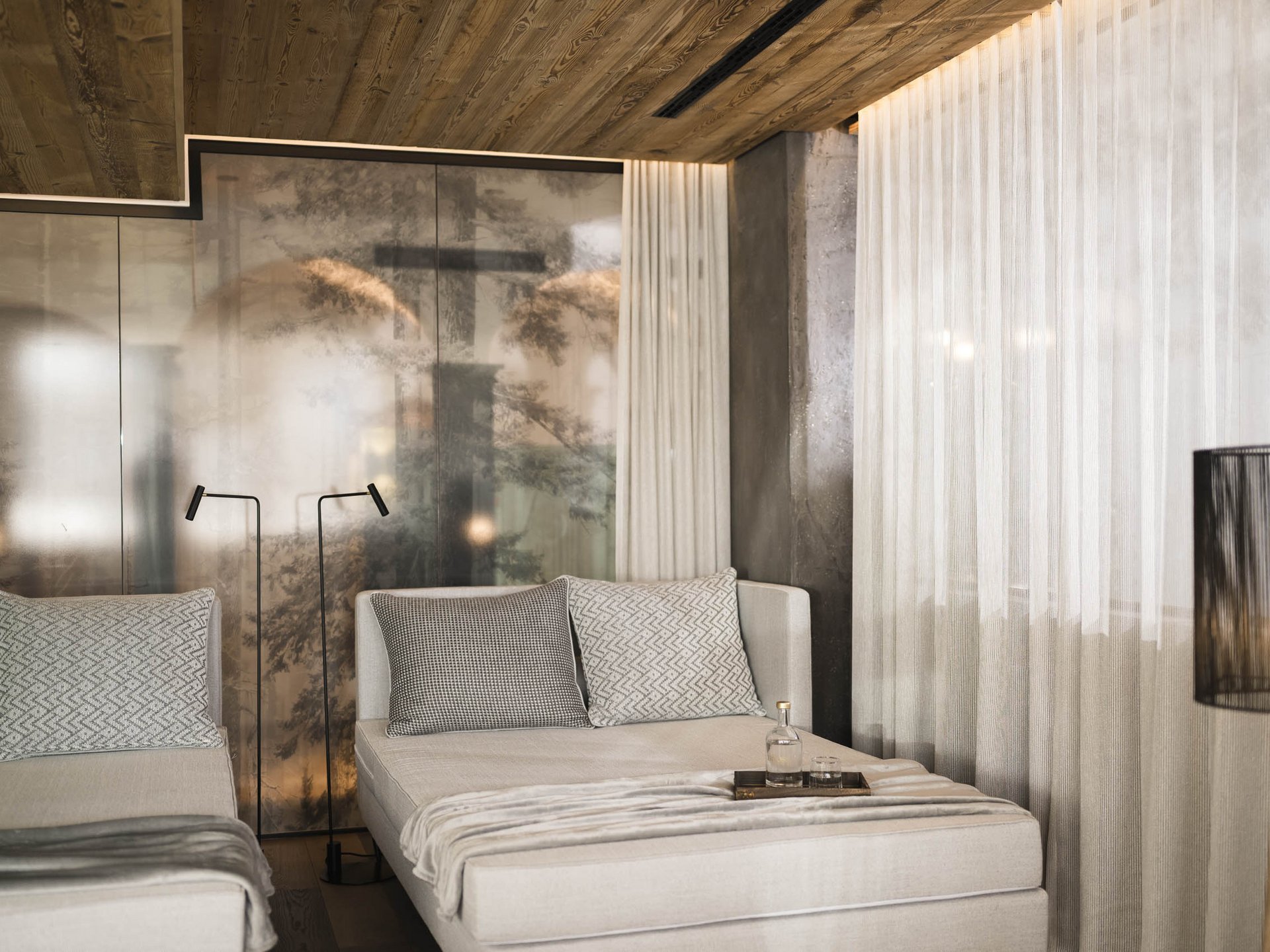 Modern living room with light armchairs, floor lamps, and textured wooden ceiling