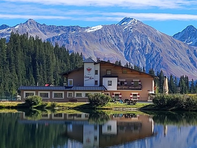 Haus am See mit Wald und Bergen im klaren blauen Himmel