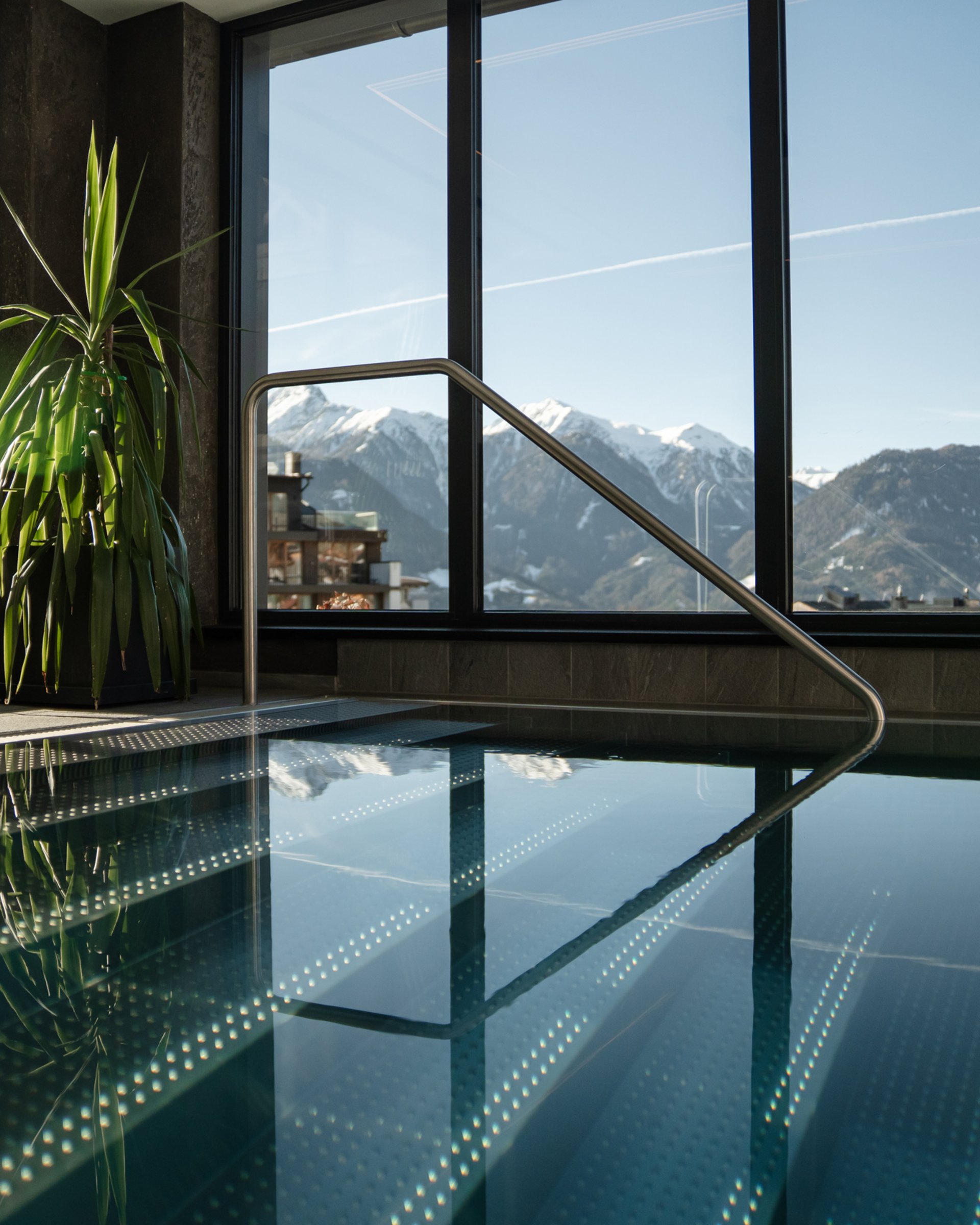 Indoor pool with panoramic windows overlooking snow-covered mountains