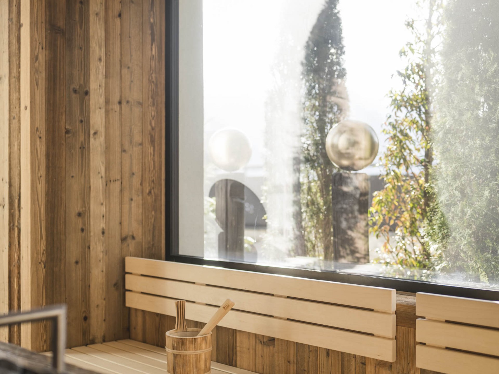 Bright modern sauna with wood paneling and large window overlooking greenery.