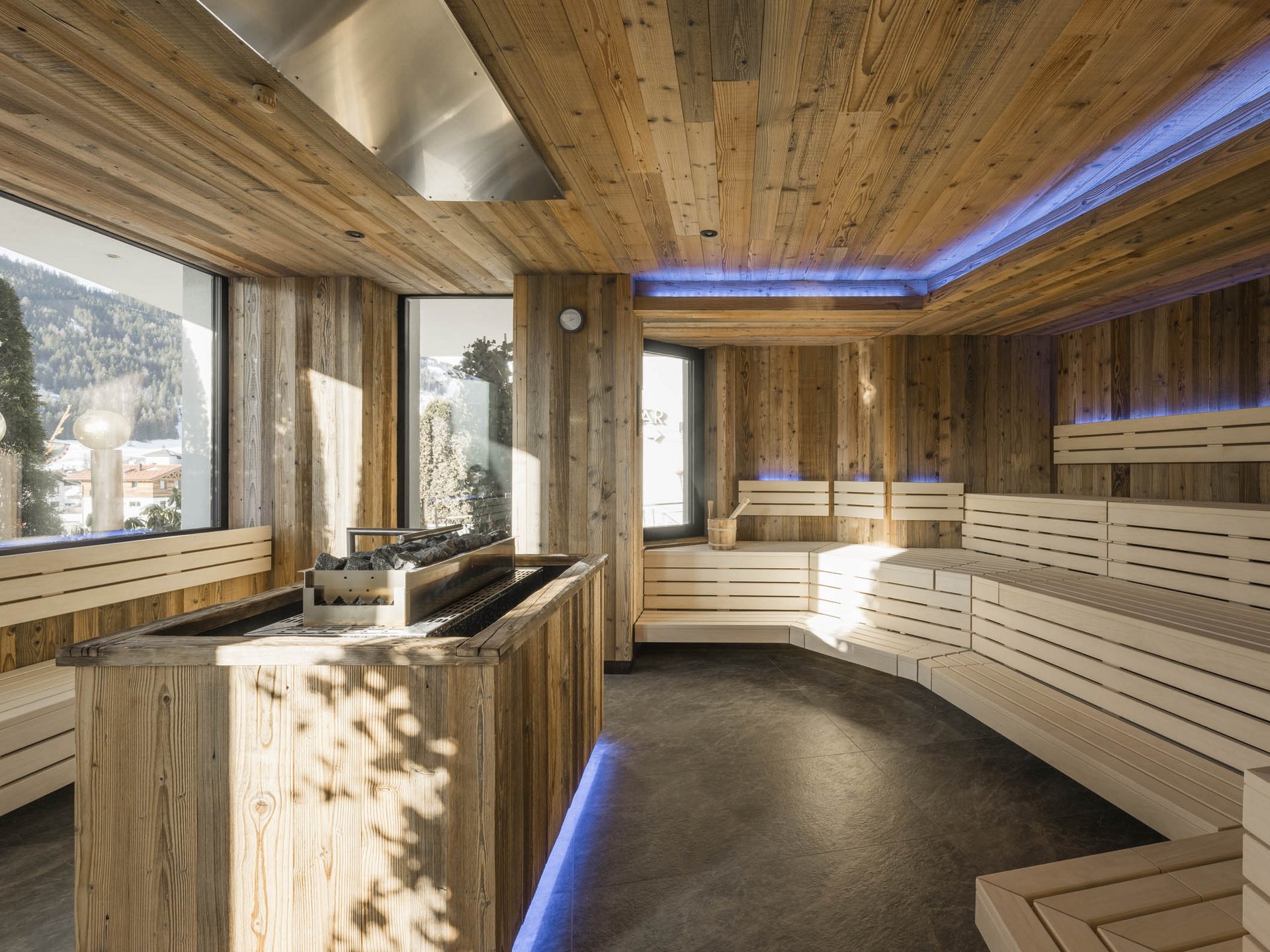 Modern wooden sauna with panoramic windows showing mountain view