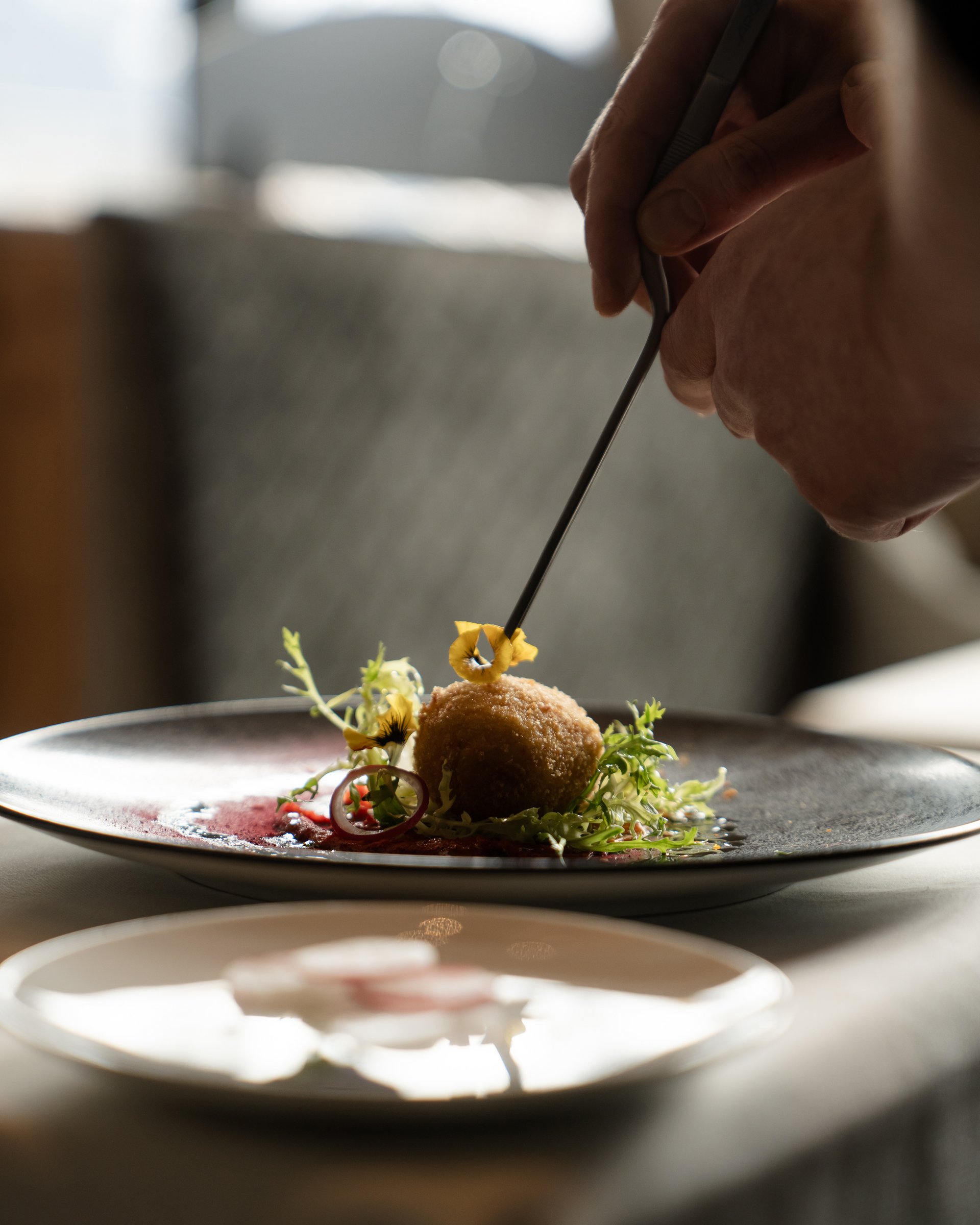 Wohlfühlurlaub im 5-Sterne-Hotel in Serfaus Hand dekoriert Gourmetgericht mit Zange auf Teller in Restaurant