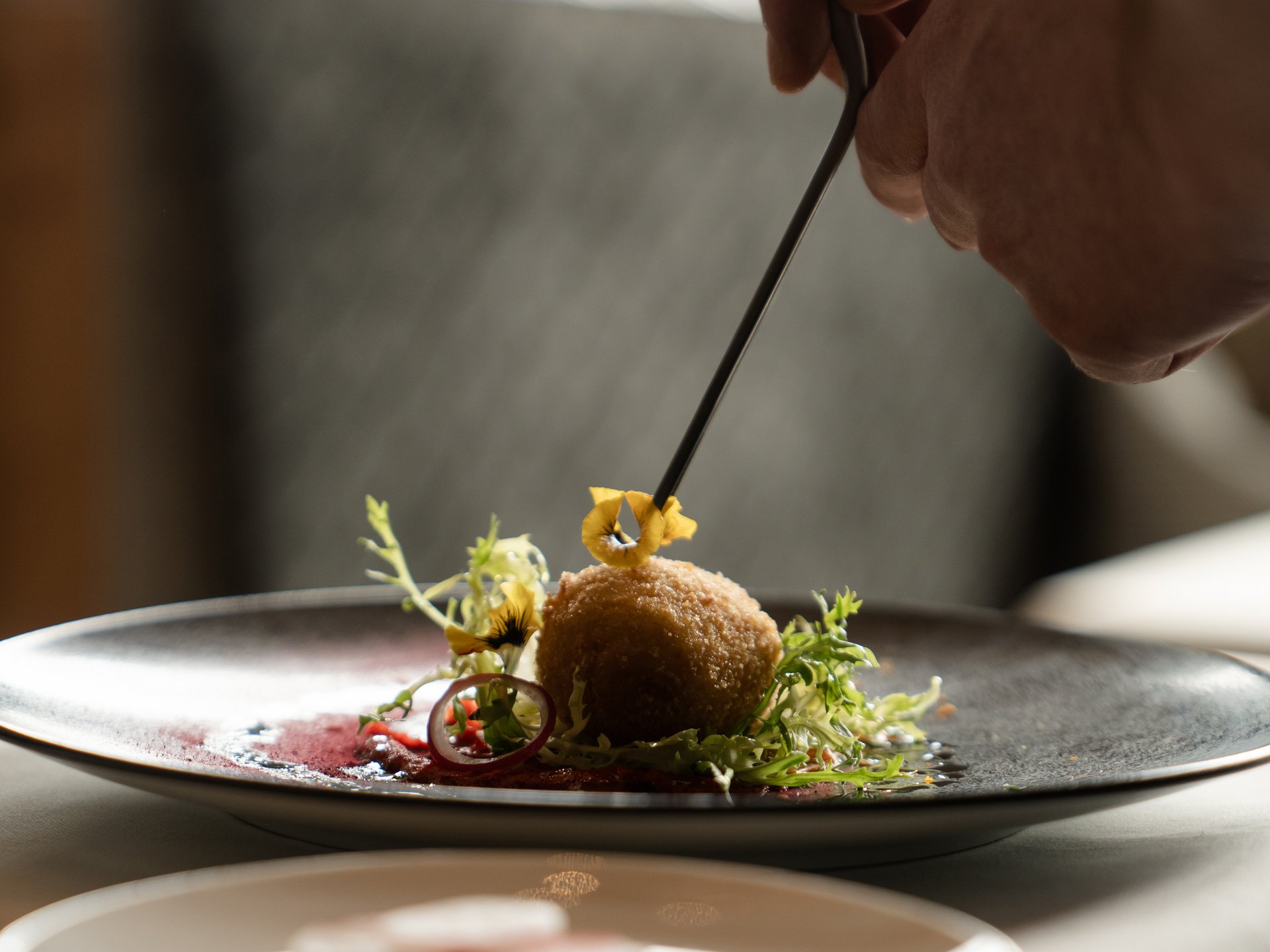 Hand dekoriert Gourmetgericht mit Zange auf Teller in Restaurant