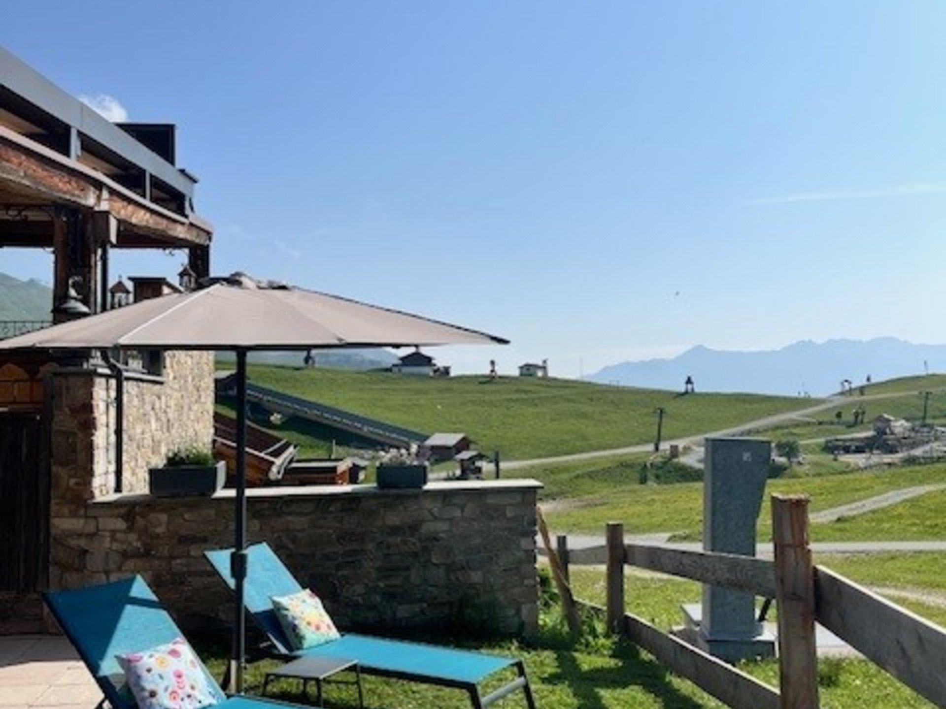 Die Cervosa Alm auf 2 000 Metern Zwei blaue Liegestühle mit Sonnenschirm auf einer Wiese mit Bergblick