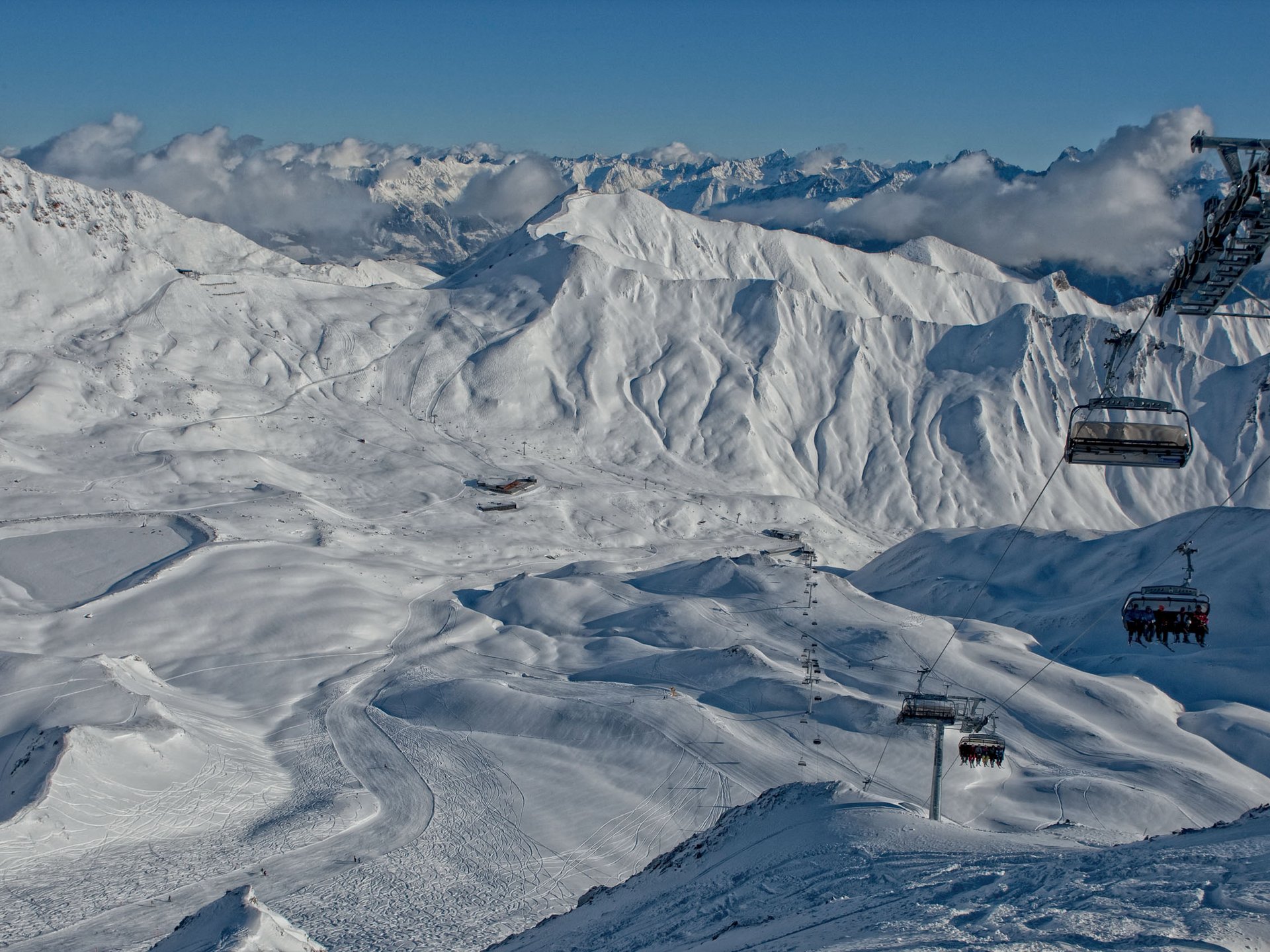 Verschneite Berge mit Skilift und einer Gruppe von Skifahrern bei klarem Himmel