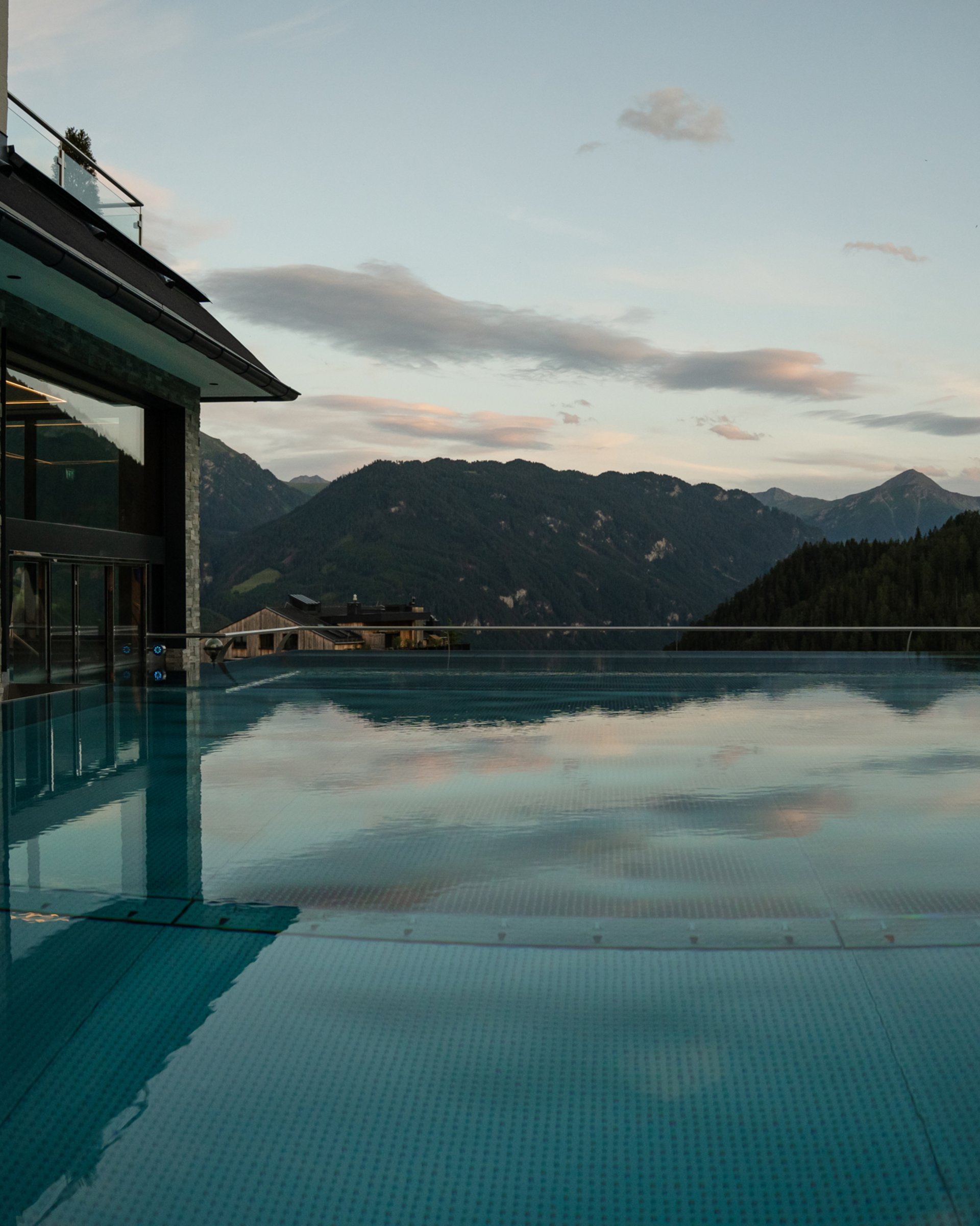 Bathing bliss at our hotel with pool in Serfaus Infinity pool with mountain view and evening sky next to modern building