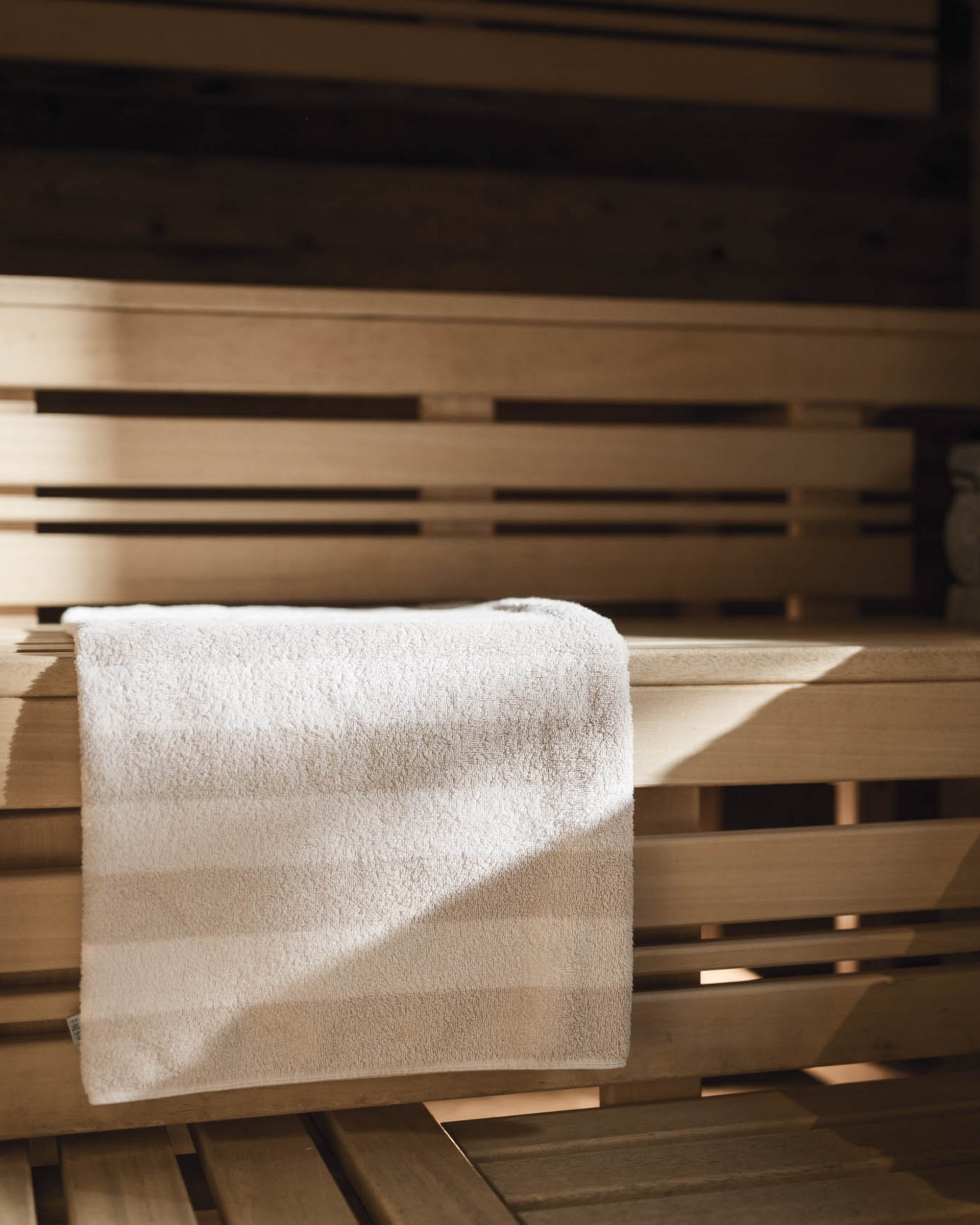 White towel on wooden bench inside a sauna with stone wall
