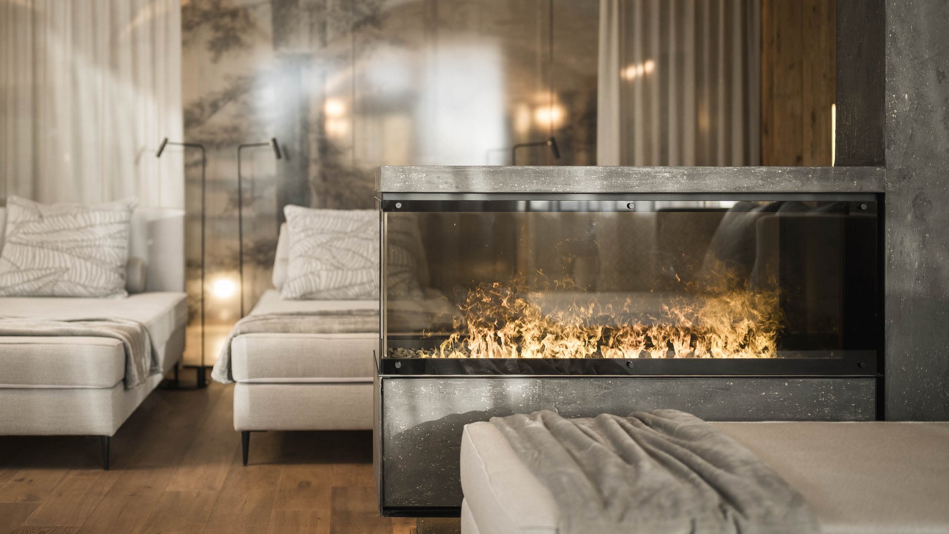 Modern room with two beds, electric fireplace, and gray blanket