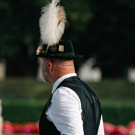Mann im Profil mit schwarzem Hut und großer weißer Feder, weißem Hemd und dunkler Weste
