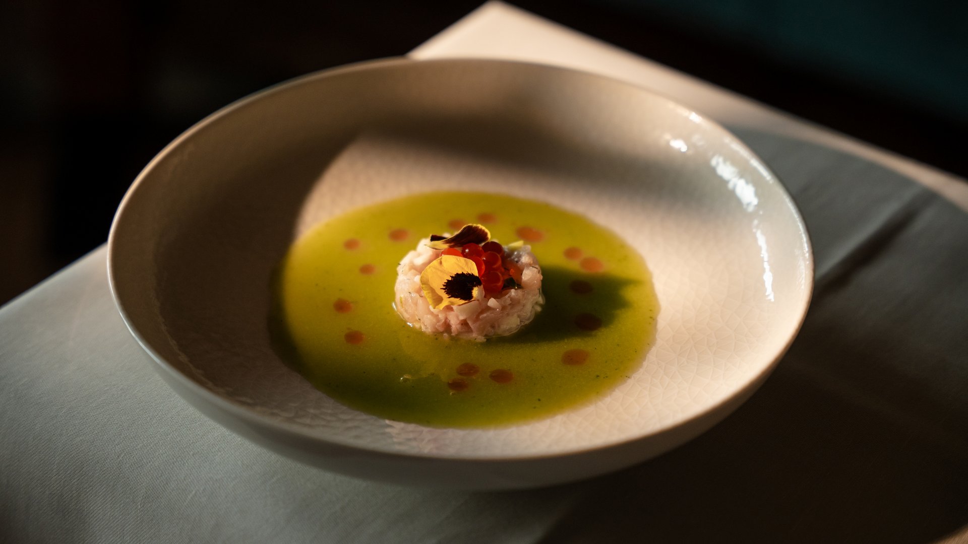 Feel-good holiday at our 5-star hotel in Serfaus Gourmet appetizer with green sauce and edible flowers in a white bowl