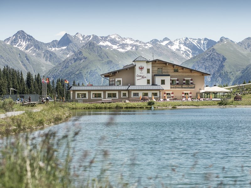 Berghütte am See mit Alpen im Hintergrund bei klarem Himmel