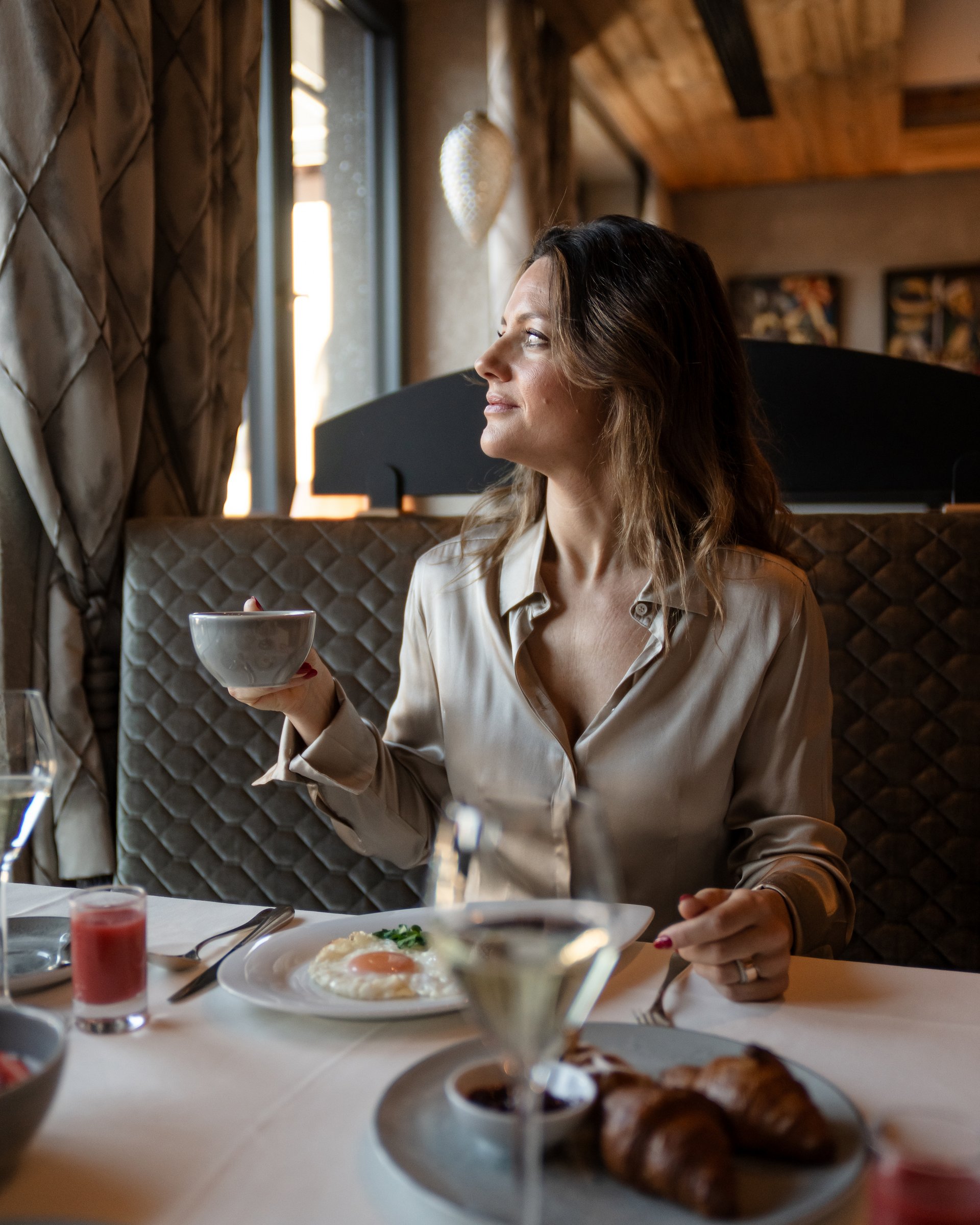 Frau hält Tasse beim Frühstück in gemütlichem Restaurant