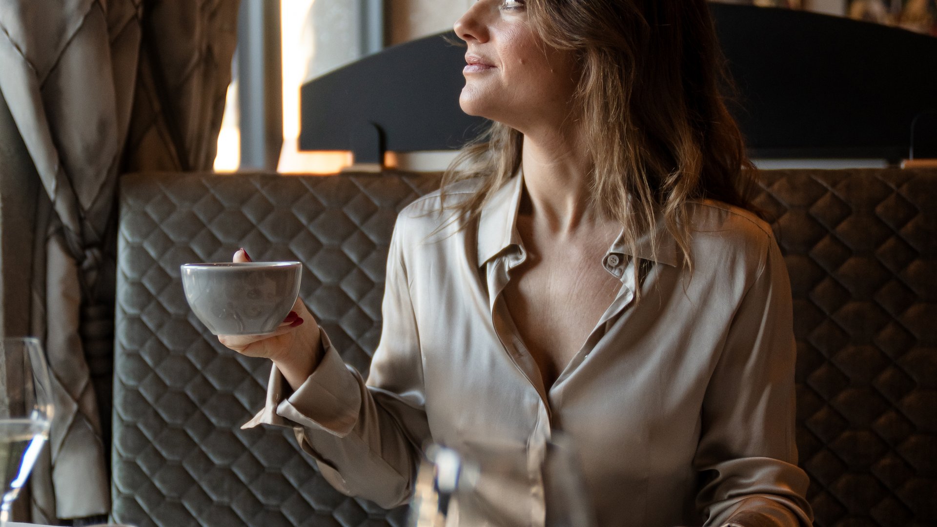 Woman holding cup while having breakfast in cozy restaurant