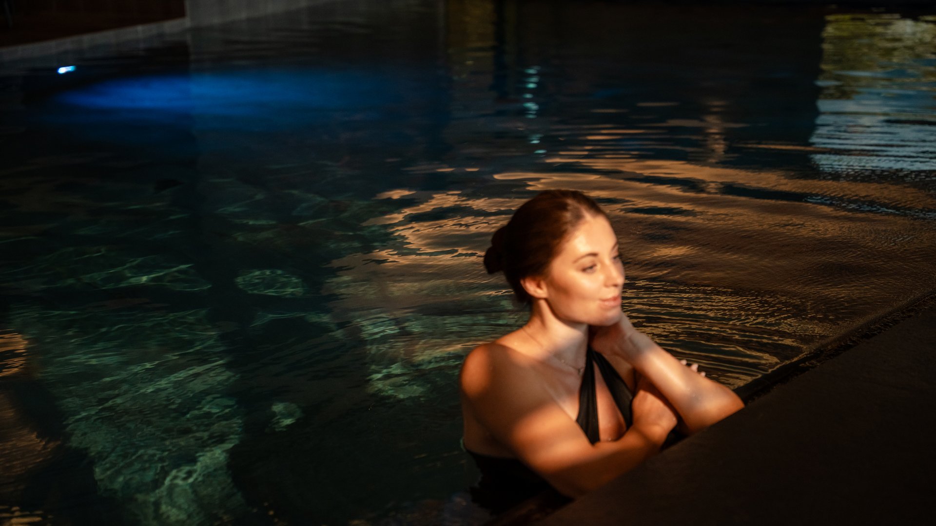 Feel-good holiday at our 5-star hotel in Serfaus Woman relaxing in swimming pool with dim lighting