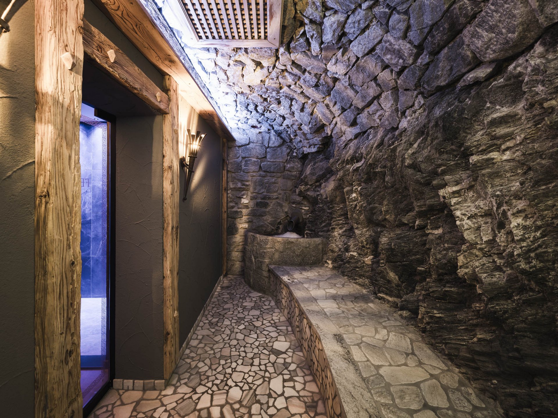 Gemauerter Entspannungsraum mit Natursteinwänden und Holzrahmen an der Tür