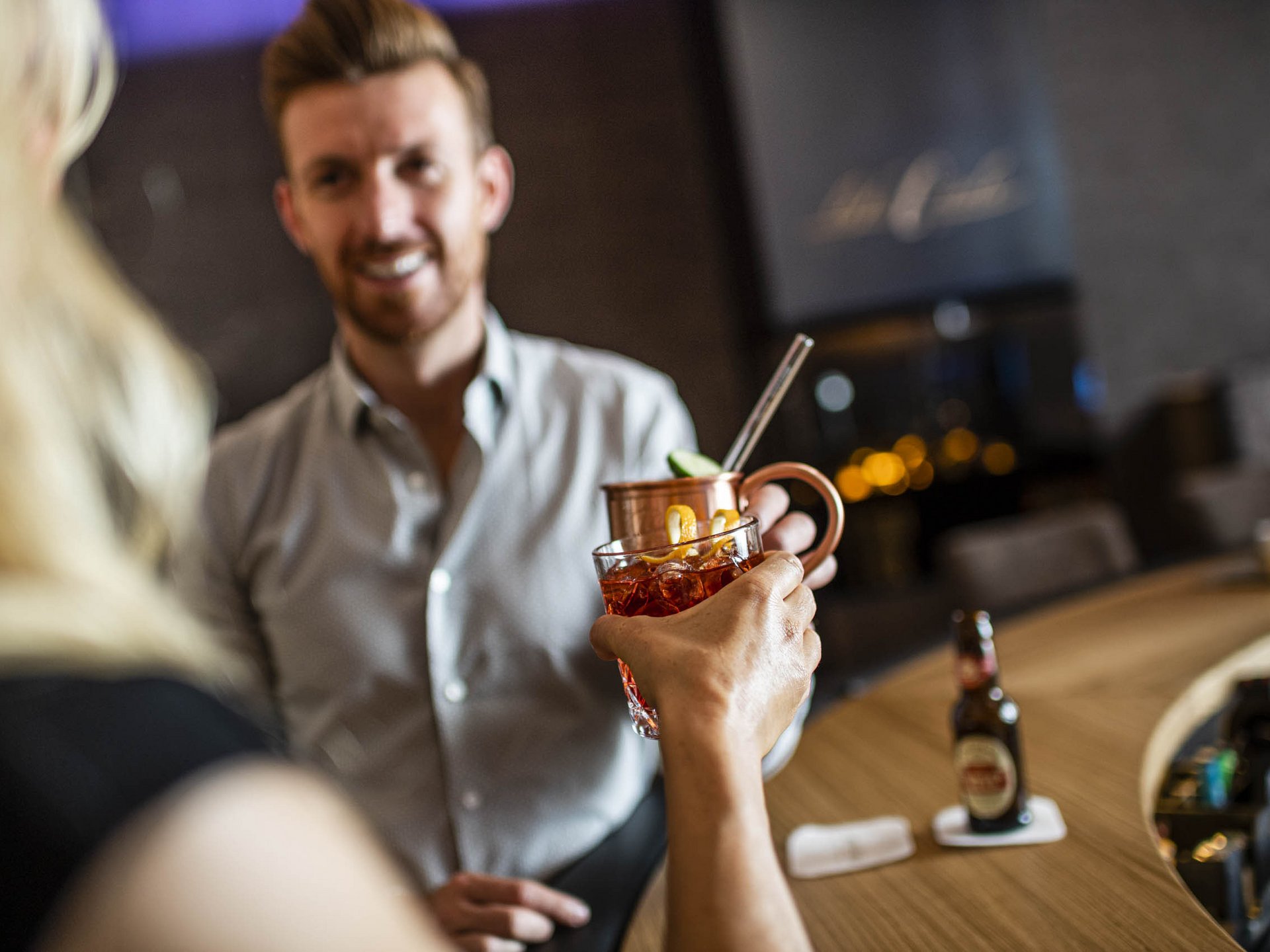 Zwei Personen stoßen an einer Bar mit Cocktails an