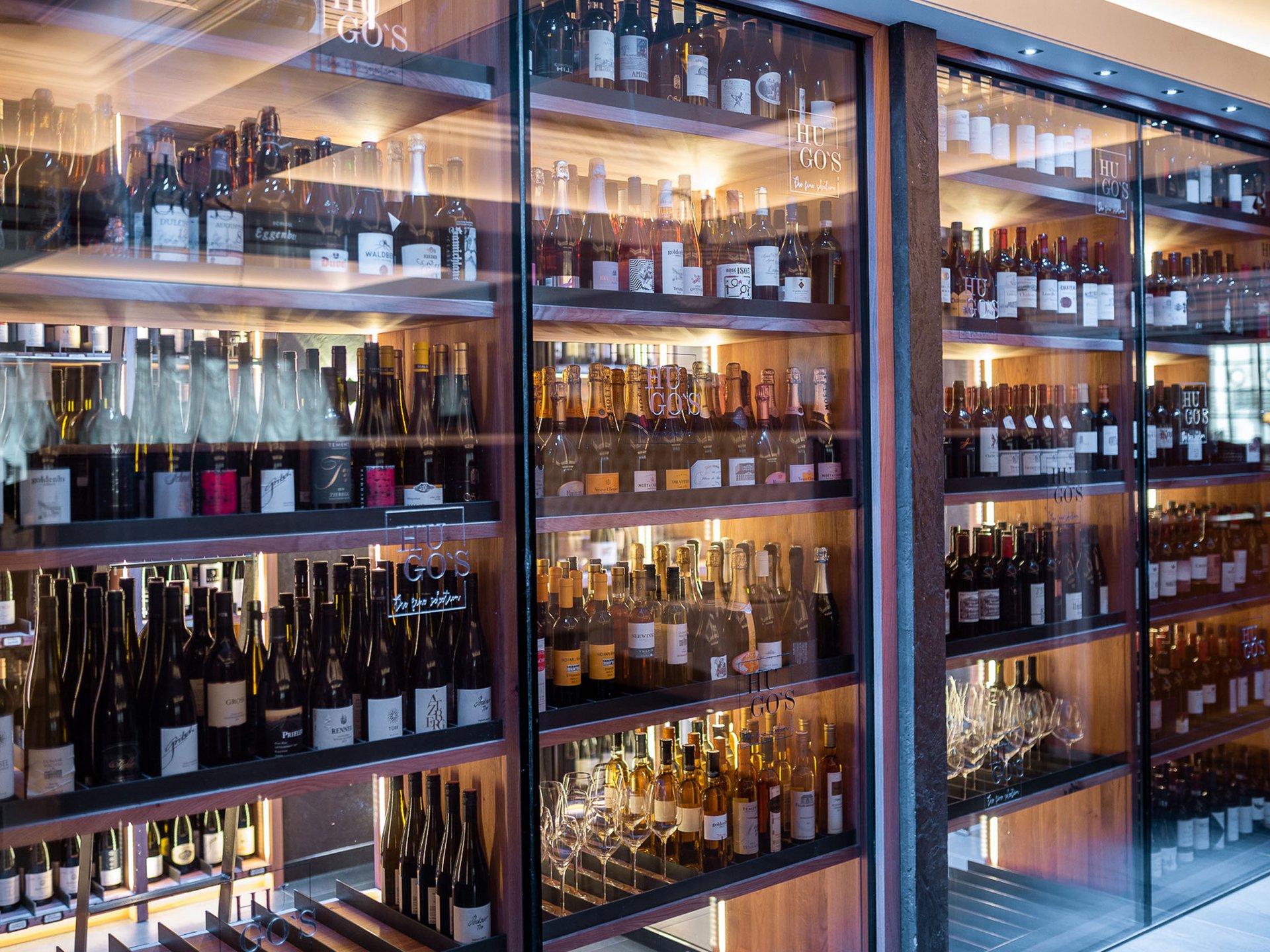 Illuminated wine shelves with various wine bottles in a modern store