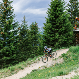 Zwei Mountainbiker fahren im Bikepark durch eine bewaldete Berglandschaft