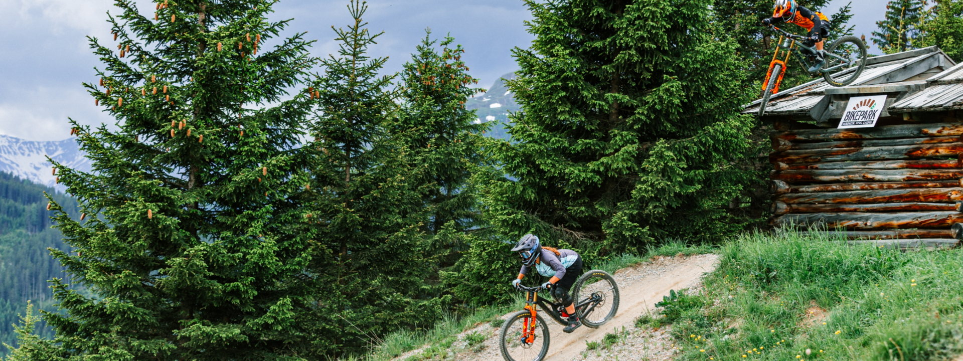 Zwei Mountainbiker fahren im Bikepark durch eine bewaldete Berglandschaft