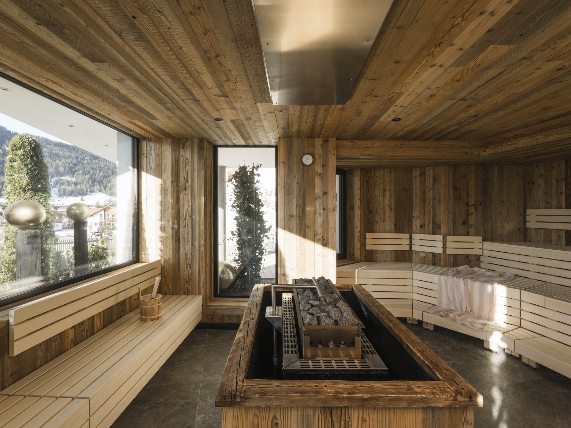 Modern sauna with light wood interior and panoramic window showing mountain view