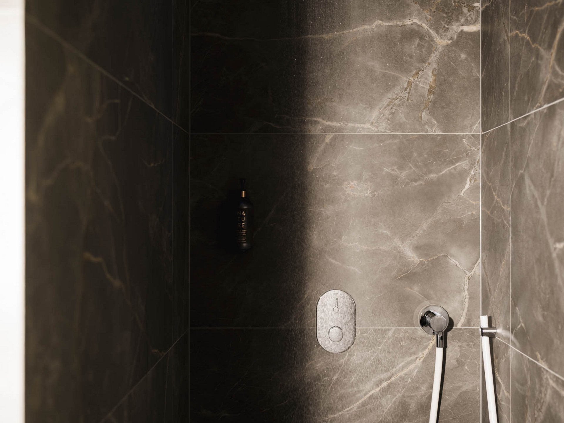 Modern shower with rain showerhead and dark marble tiles