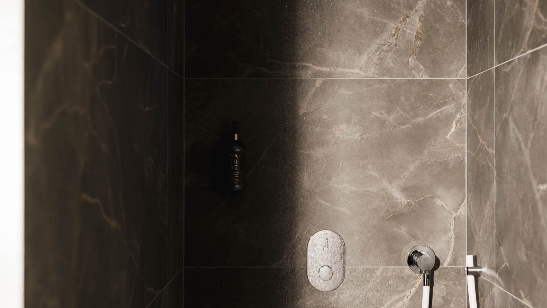 Modern shower with rain showerhead and dark marble tiles