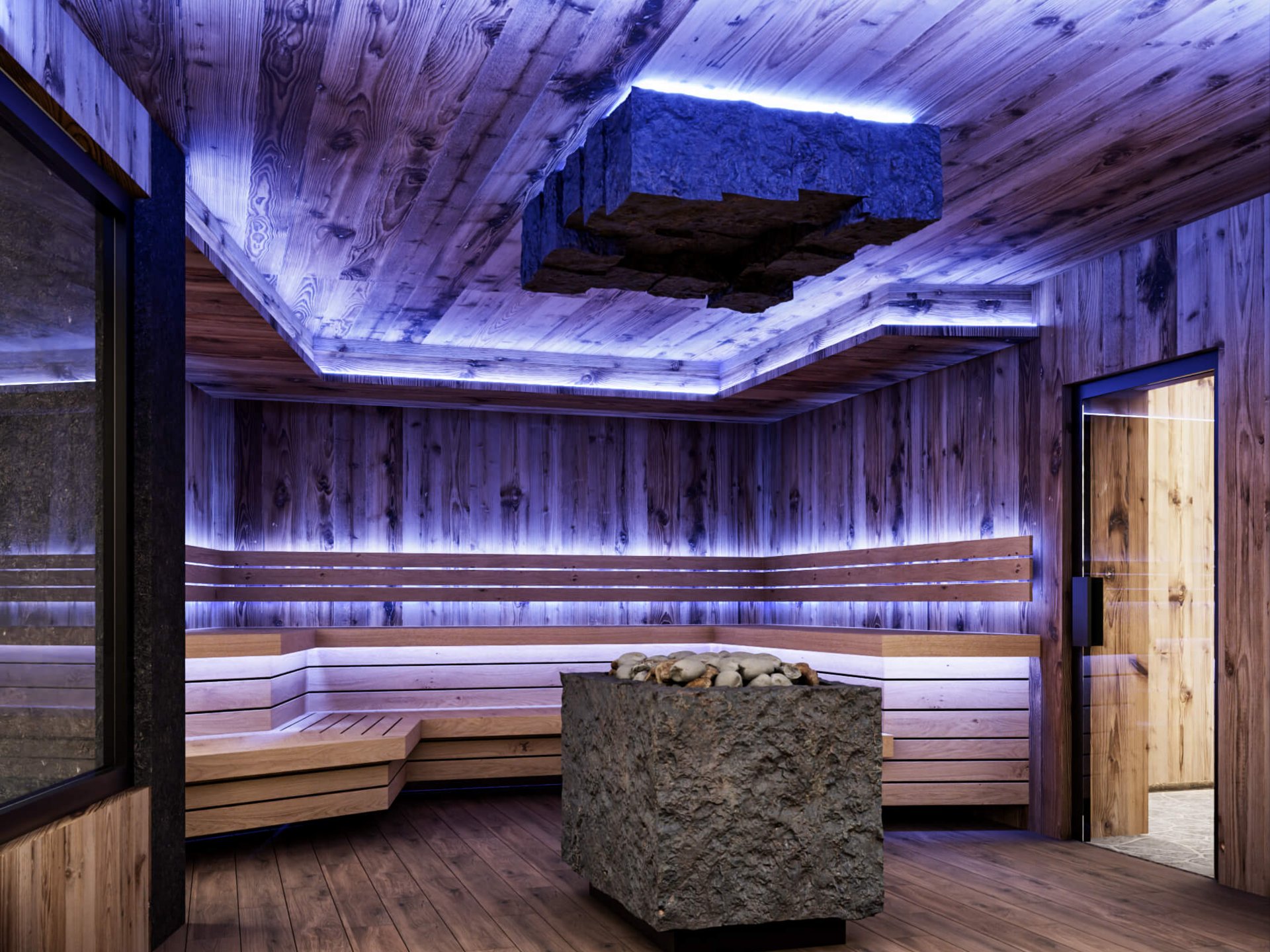 Modern sauna with wood paneling, stone heater, and indirect blue lighting