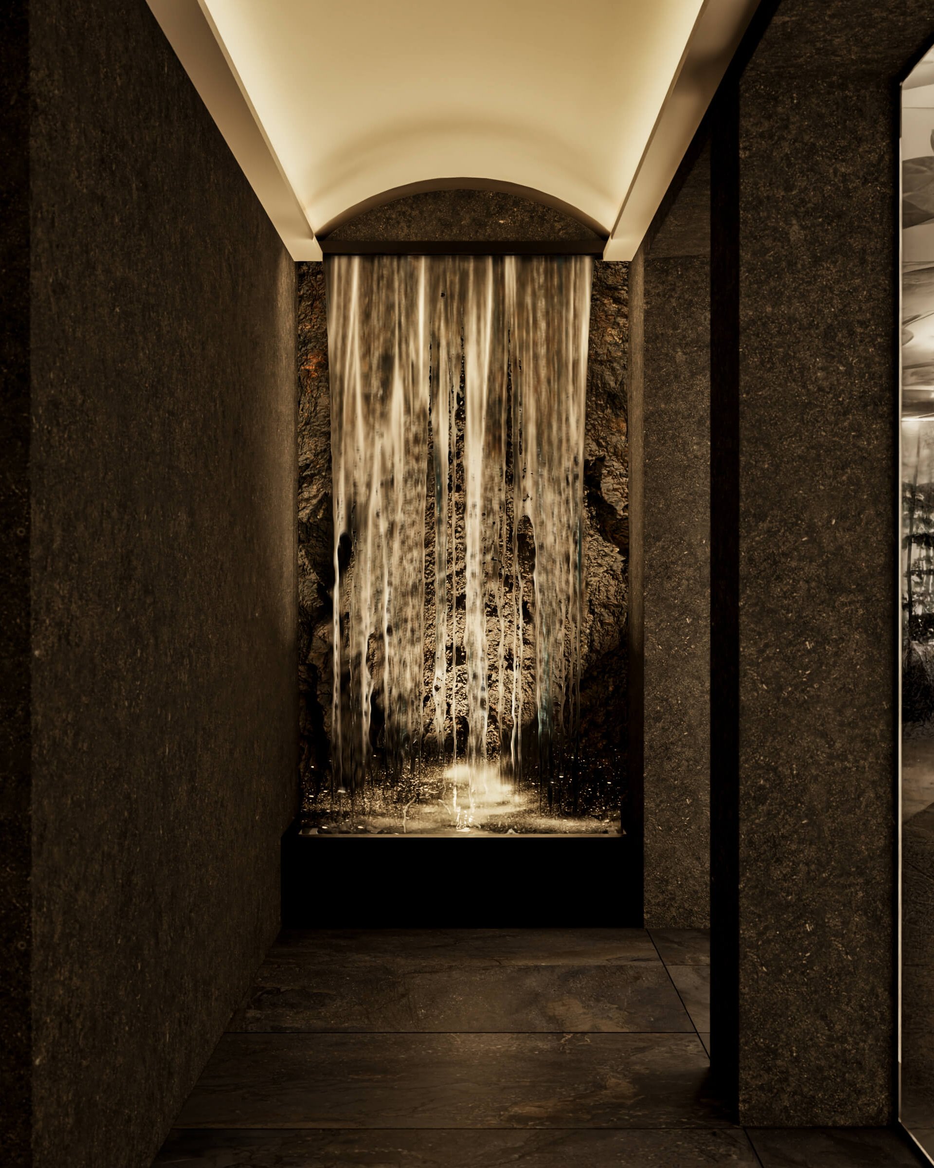 Interior space with illuminated waterfall and dark stone walls