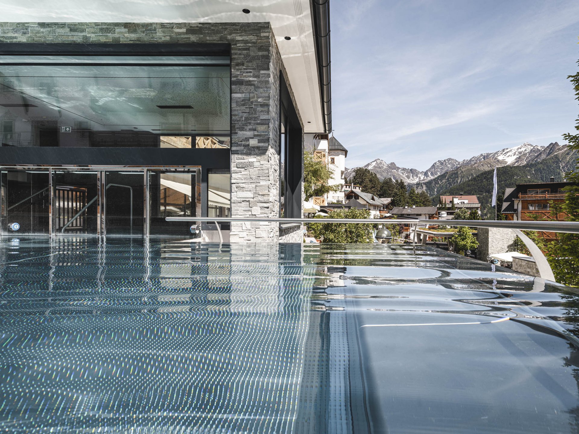 Infinity pool overlooking mountains and modern building facade