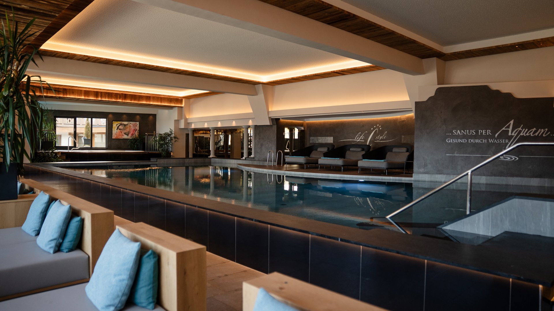 Interior of a modern indoor pool with seating area and wooden ceiling