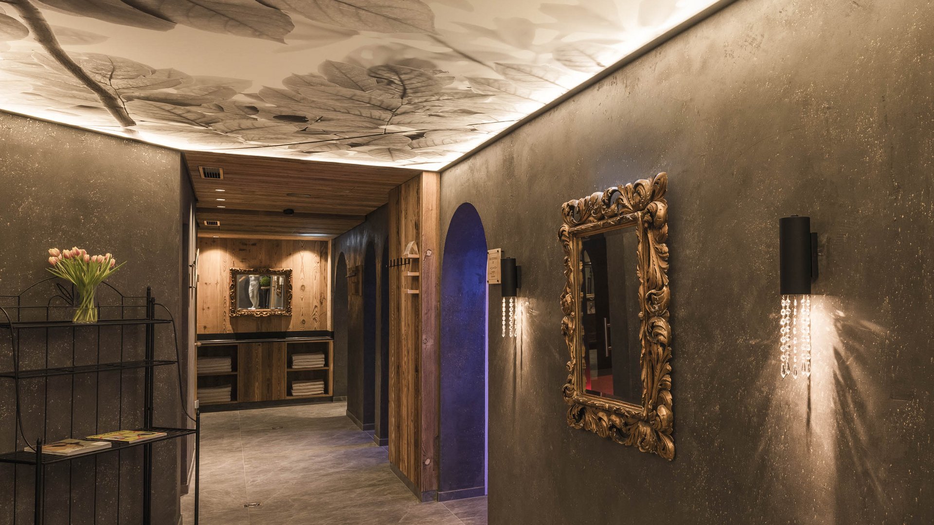 Hallway with ornate mirror frame lighting and leaf-patterned ceiling