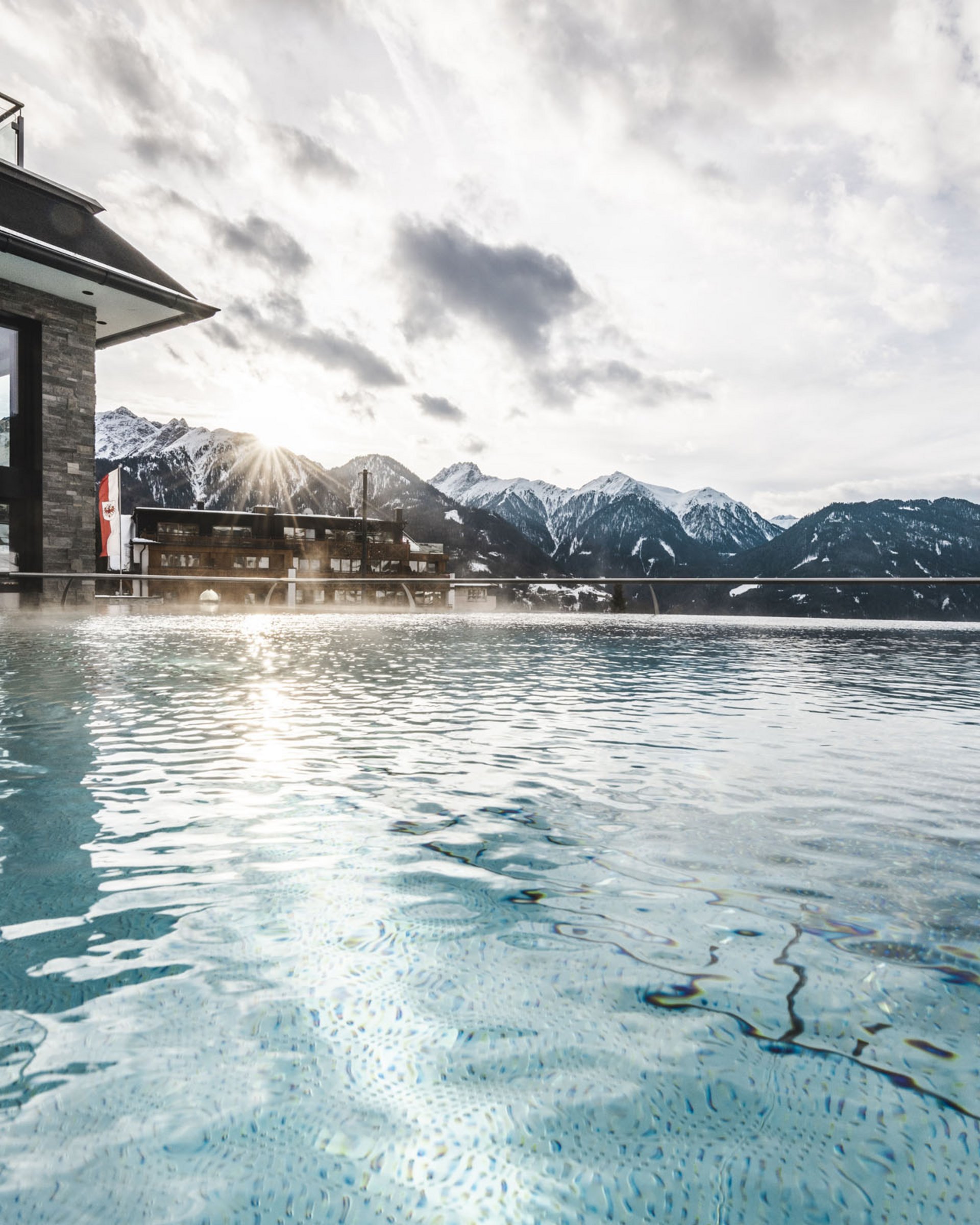 Outdoor pool with mountain view and sunlight on a cloudy day