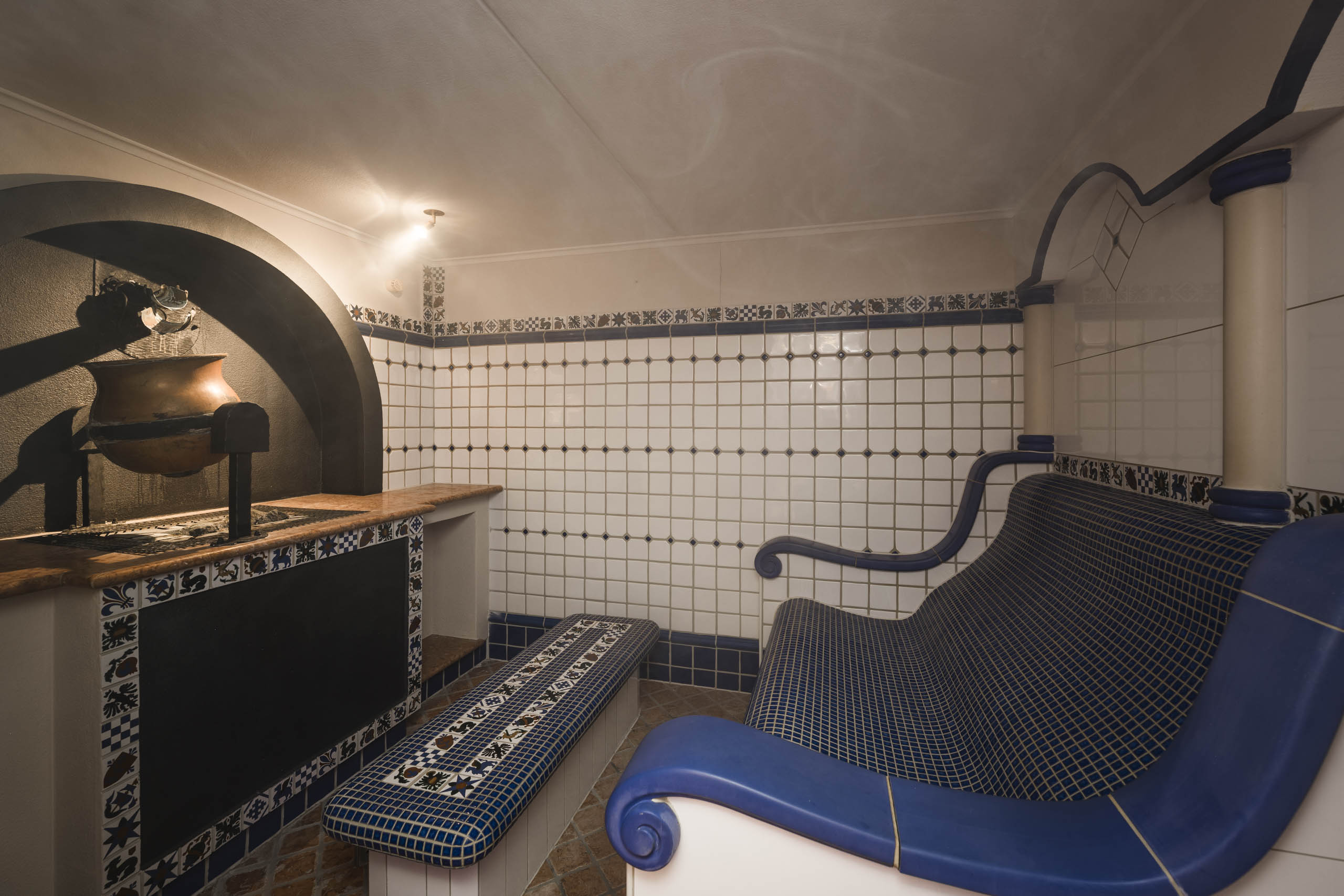 Historic tiled stove with blue tiled bench and sofa in a traditional room